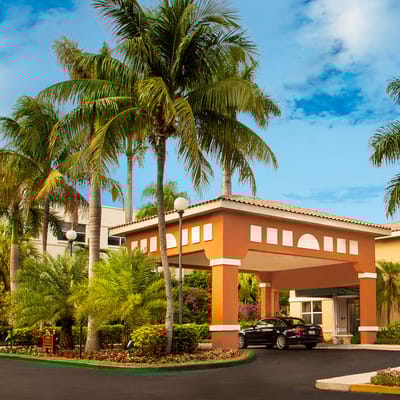Entrance with palm trees and landscaping at The Palace Royale at Kendall