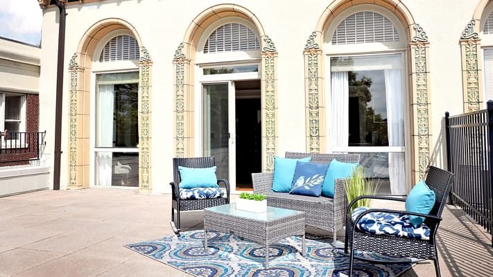 Cozy patio area with seating and decorative rug.