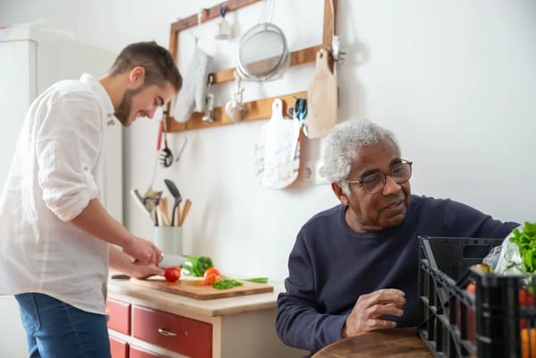 A resident and staff member preparing vegetables in the kitchen