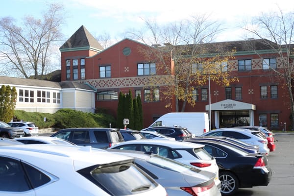Exterior view of Evergreen Woods senior living facility with parked cars