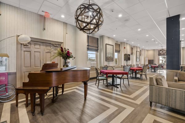 Interior view of a common area with dining tables and a piano