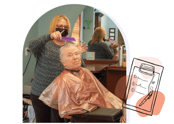 Resident receiving a haircut from a staff member