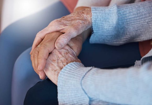 Two elderly hands holding each other in comfort