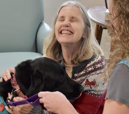 Resident smiling and playing with a dog indoors