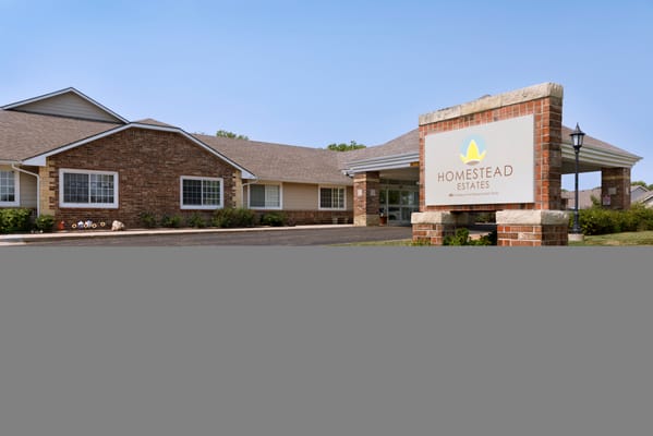 Facility building exterior with sign and landscaped area