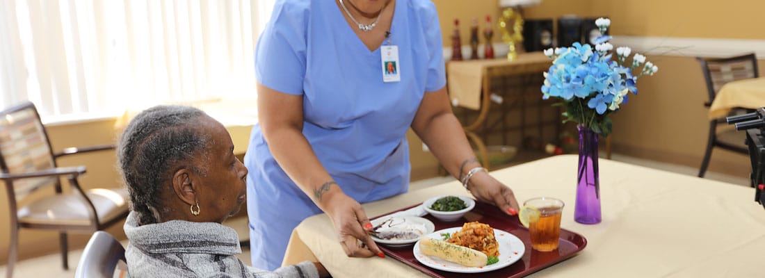 Staff serving food to a resident in a dining area