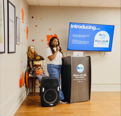A staff member speaking at an event in a decorated room