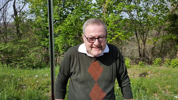 Elderly man smiling outdoors in a lush garden