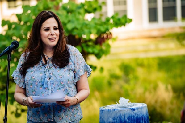 Woman speaking at an outdoor event in a garden