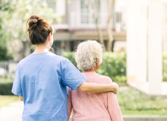 A caregiver assisting a resident in an outdoor space