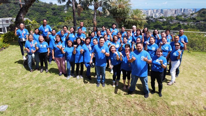 Group photo of staff members in blue shirts outdoors