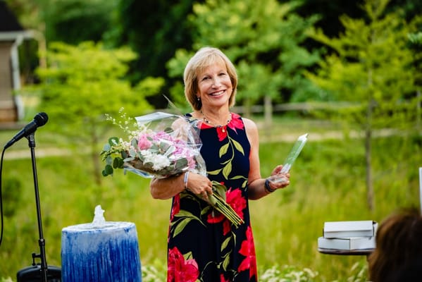 A woman holding flowers at an outdoor celebration