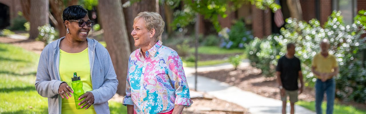 Two residents walking together in a garden area