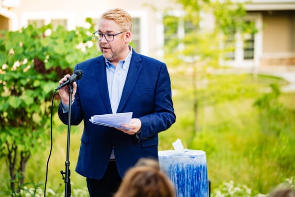 A speaker at an outdoor event in a garden setting