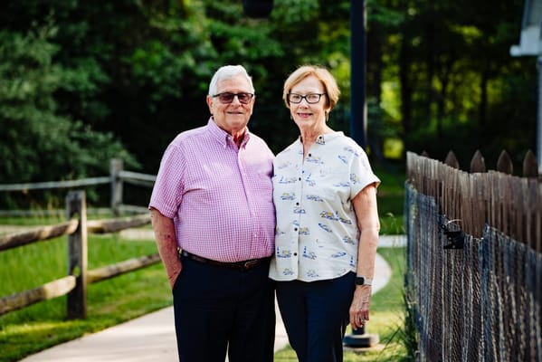 Two smiling residents posing outdoors by a pathway