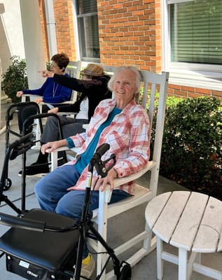 Residents enjoying time on a porch in rocking chairs
