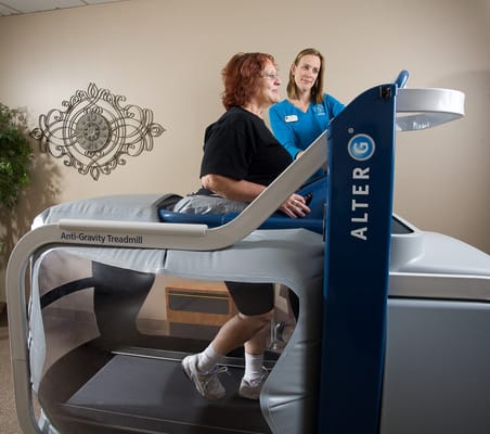Resident using an anti-gravity treadmill with staff assistance