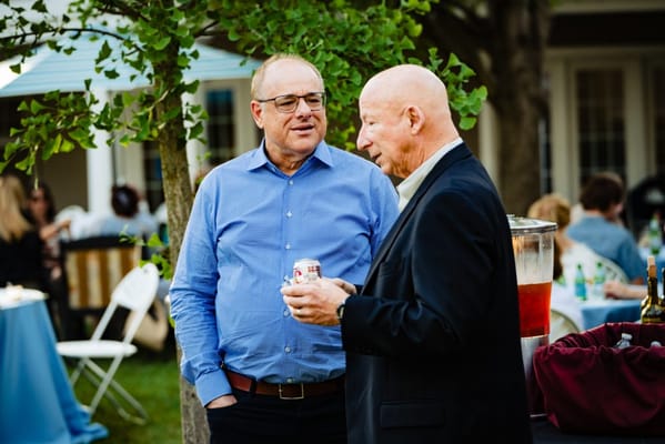 Two men conversing at an outdoor gathering