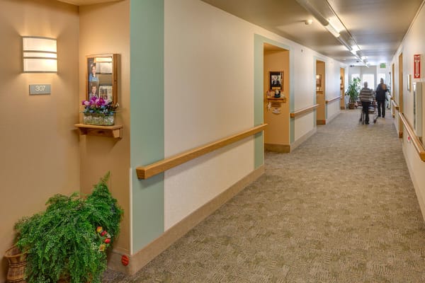 A hallway in an assisted living facility with decorations and residents