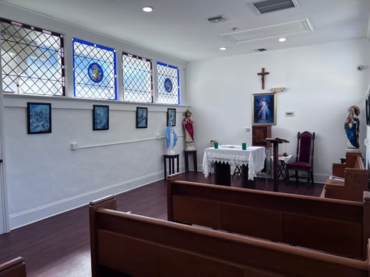 Interior view of a chapel with wooden pews and artwork
