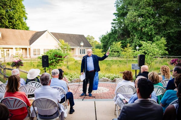 A speaker addressing an audience outdoors at a facility event
