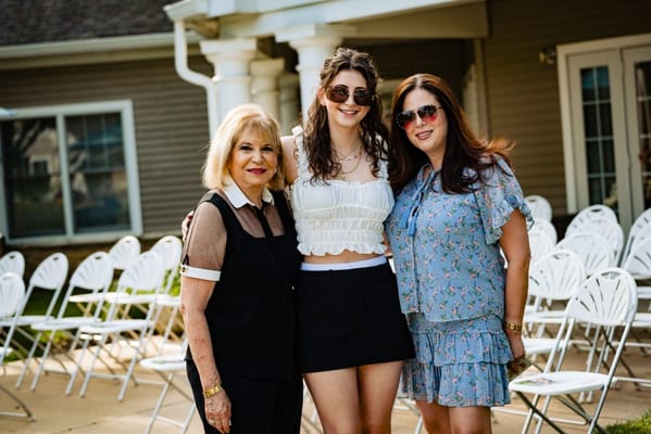 Three women posing together outdoors at a gathering