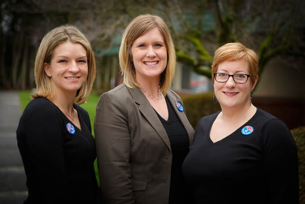 Three staff members smiling outdoors