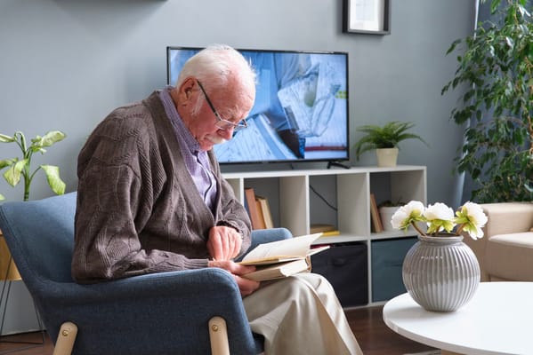 An elderly man reading a book in a common area