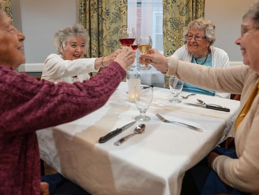 Residents toasting glasses in a dining setting