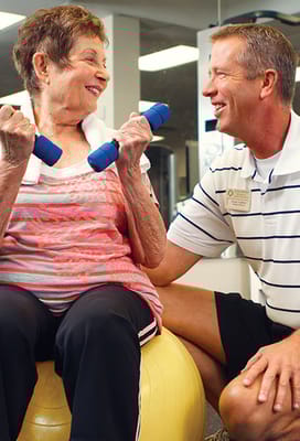 Resident exercising with staff support in a fitness area