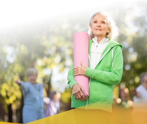 Senior participating in outdoor exercise with a yoga mat