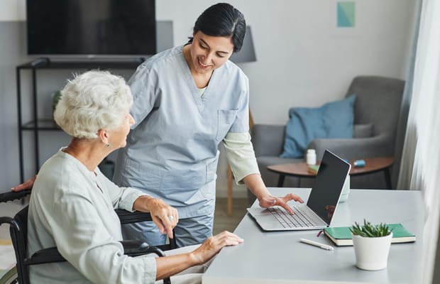 Staff assisting an elderly resident in a cozy interior setting