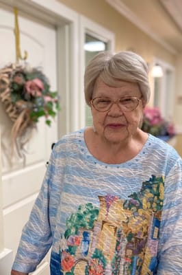 Resident smiling in a colorful top in a hallway