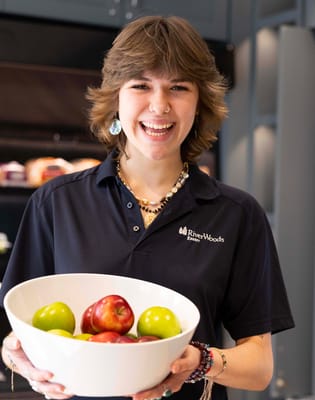 Staff member holding a bowl of fresh apples in the kitchen