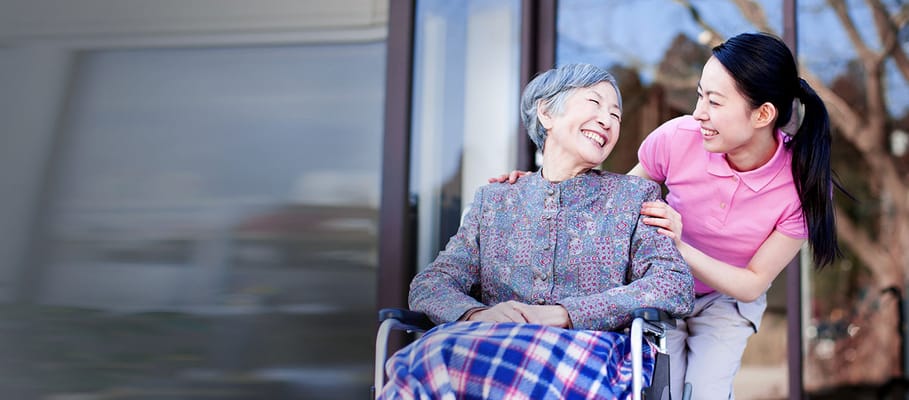 Staff member assisting a smiling resident in a wheelchair
