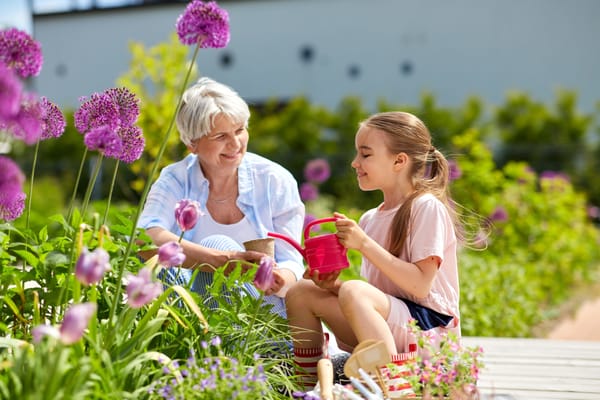 Senior woman and girl gardening together in vibrant flowers
