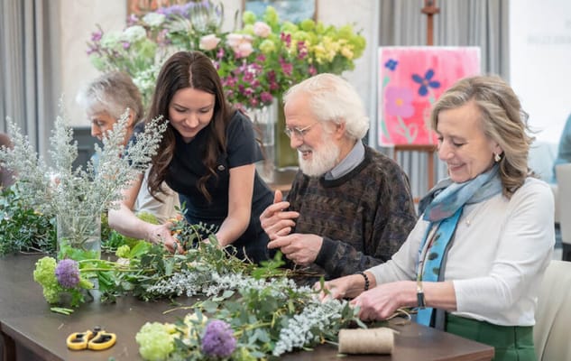 Residents and staff making flower arrangements together.