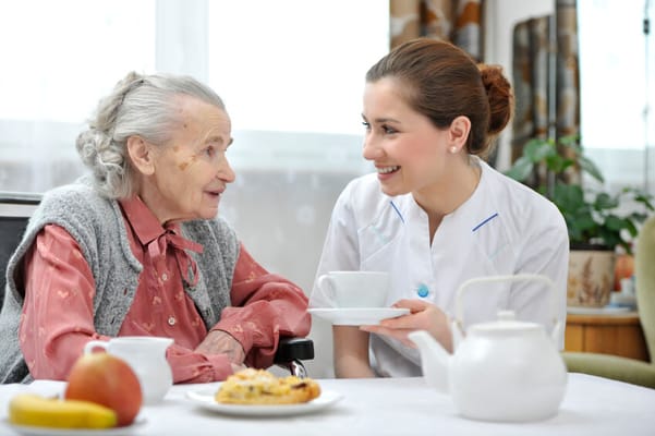 Caregiver serving tea to a resident in a cozy setting