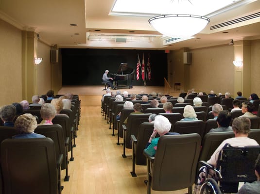 Residents enjoying a piano performance in an auditorium