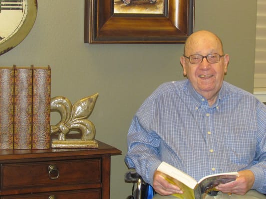 Resident smiling while reading in a cozy interior setting