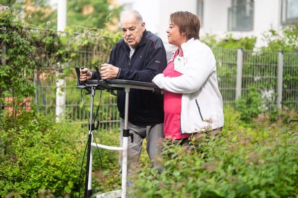 Staff assisting resident in a garden setting