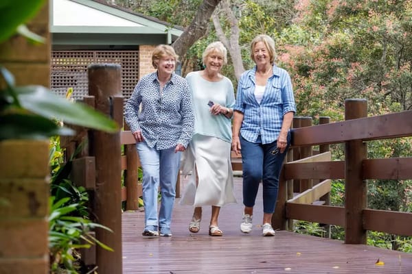 Three women enjoying a walk on a garden pathway