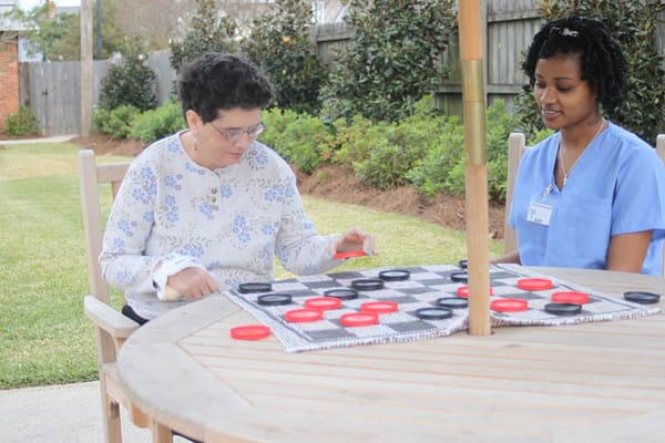 Residents playing checkers outdoors in a garden