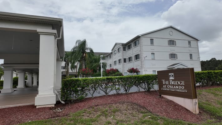 Exterior view of The Bridge at Orlando with landscaping and sign.