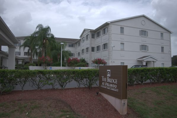 The Bridge at Orlando senior living facility exterior with a garden and signage