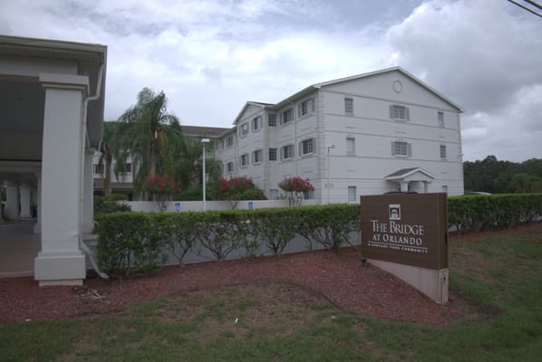 Exterior of The Bridge at Orlando senior living facility with sign.