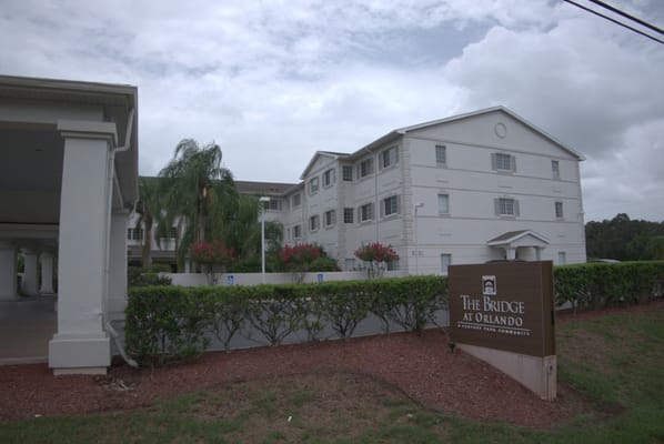 Exterior view of The Bridge at Orlando with landscaping and sign.