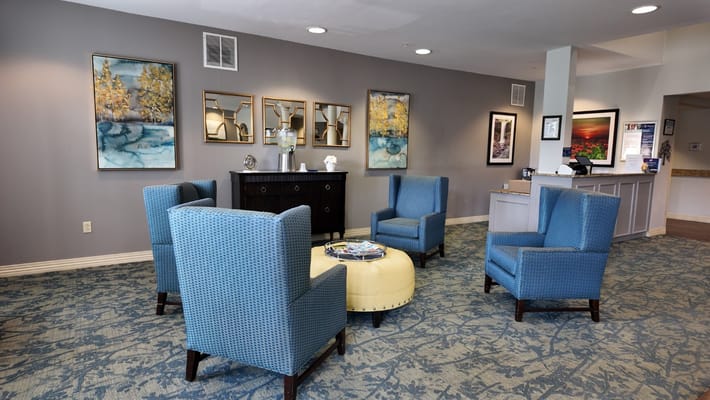 A cozy lobby area with blue chairs and artistic wall decor.