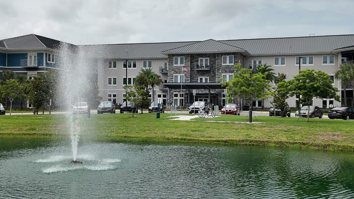 A fountain in a pond in front of The Landings at Gentry Park