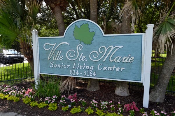 Sign for Ville Ste Marie Senior Living Center with flower garden.